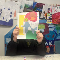 A person holding their artwork in front of their face