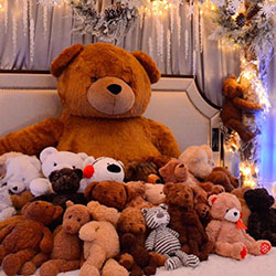 Teddy bears of various sizes arranged on a holiday-themed bed