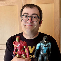 A young man wearing glasses holds action figures