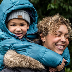 A mom gives her son a piggy-back ride