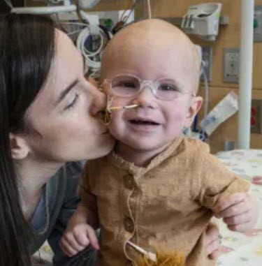 Mother kisses her baby on the cheek