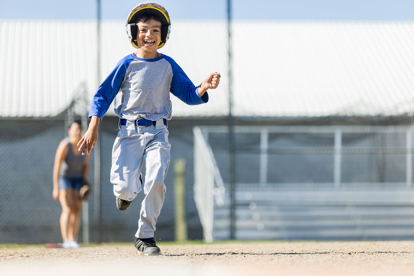A joyous boy runs the bases in a baseball game.