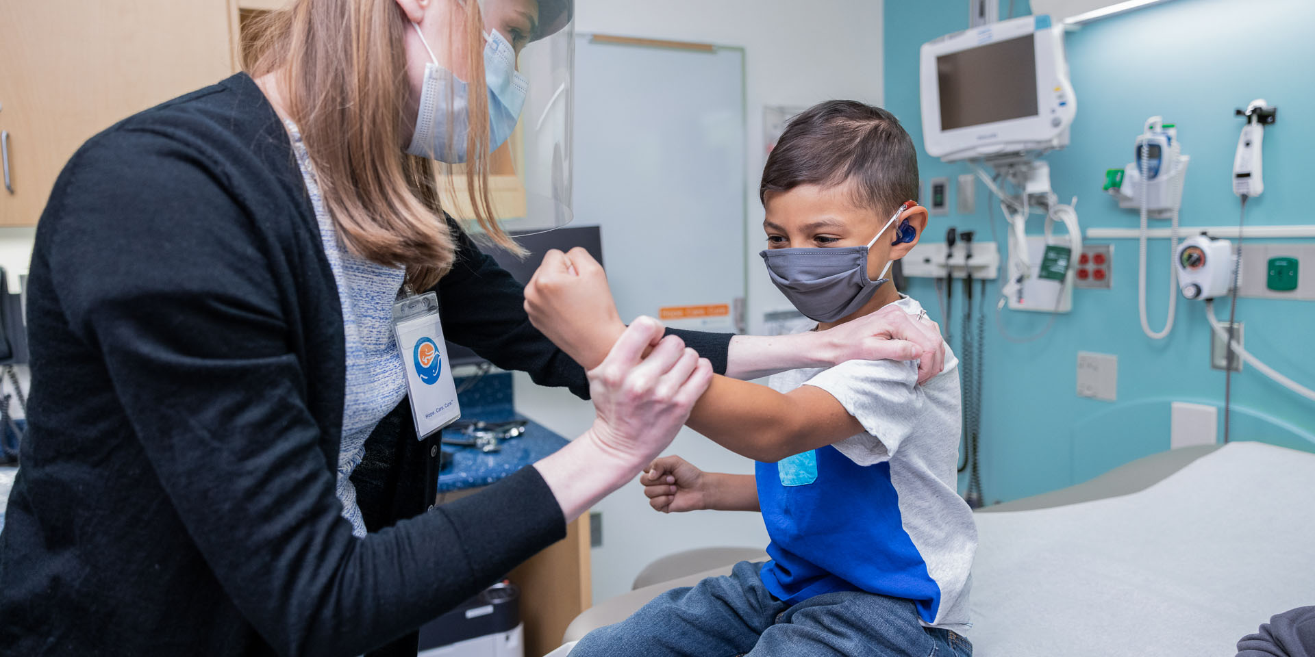A boy flexes his arm for a Seattle Children's provider