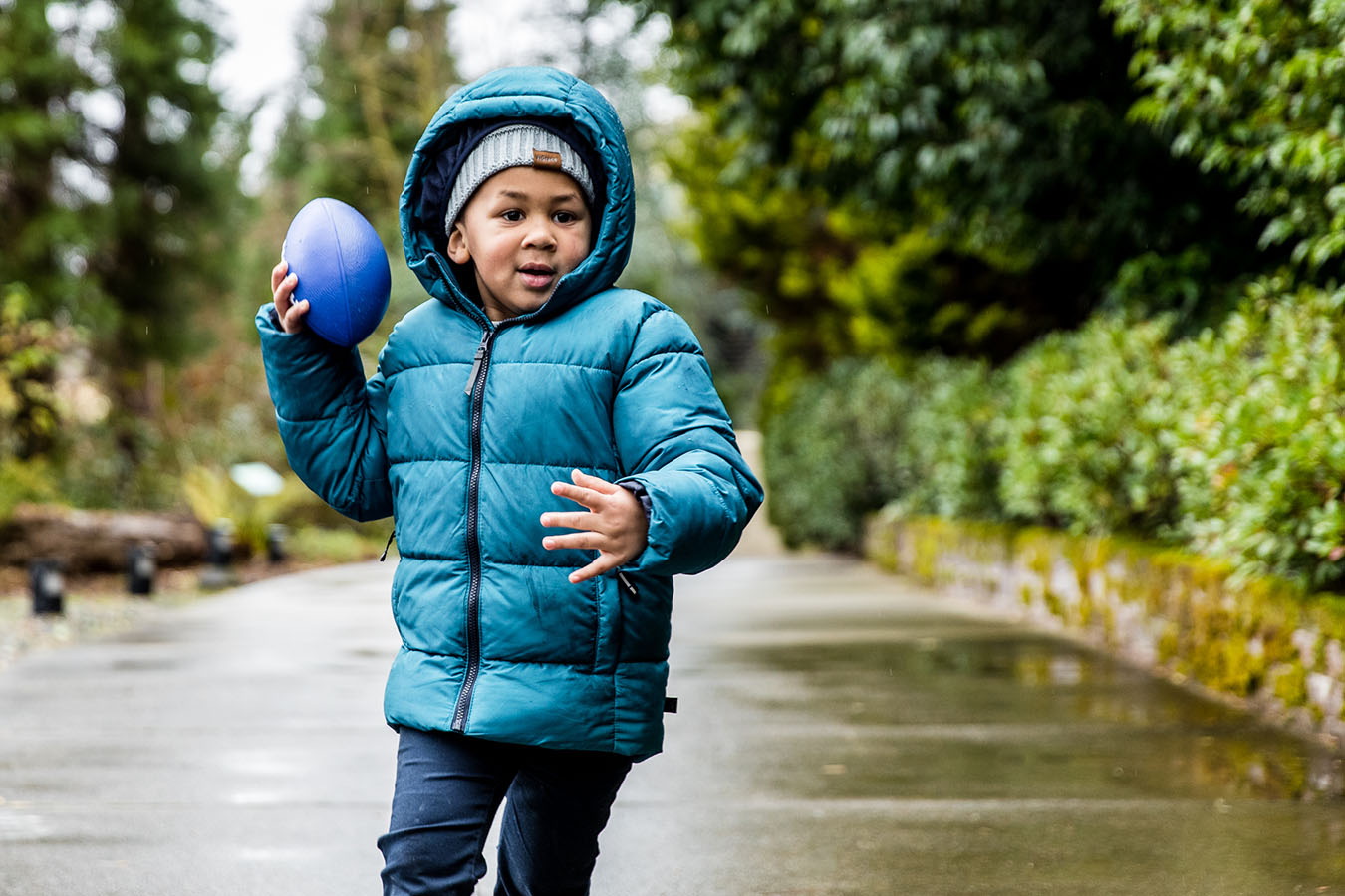 A boy runs outside with a football