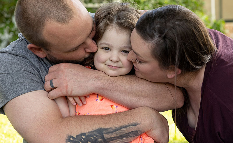 A family hugs in their front yard