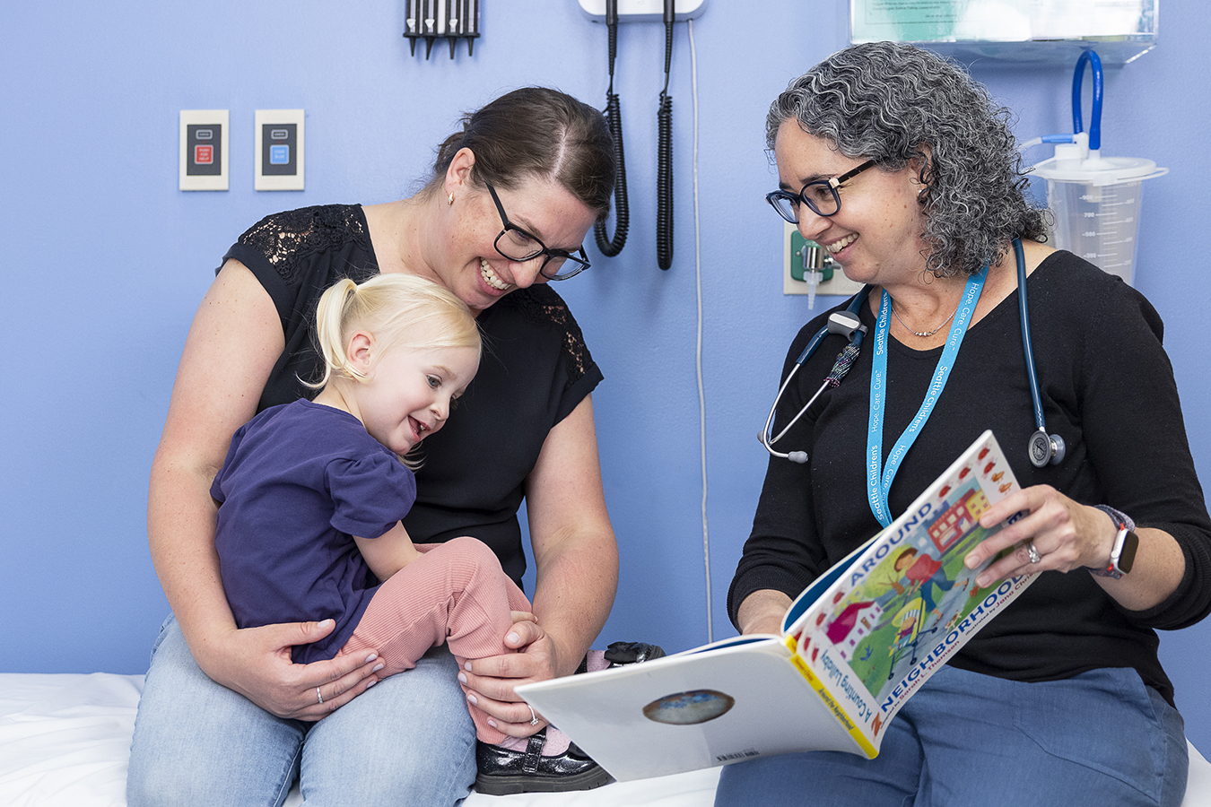 Provider showing a book to mother and daughter