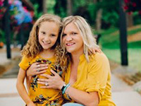 A mother holds her daughter on a sidewalk