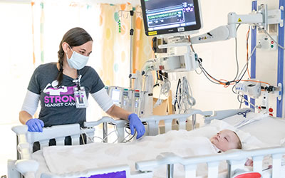 A nurse looks at a sleeping child in a hospital bed