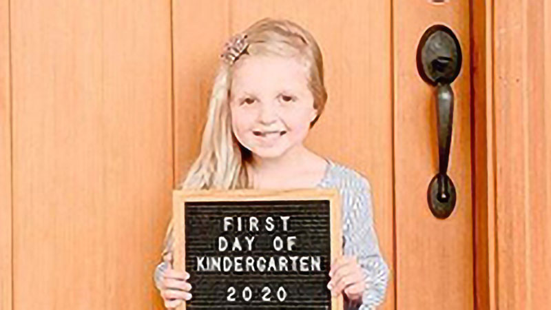 A girl poses on her first day of kindergarten in 2020