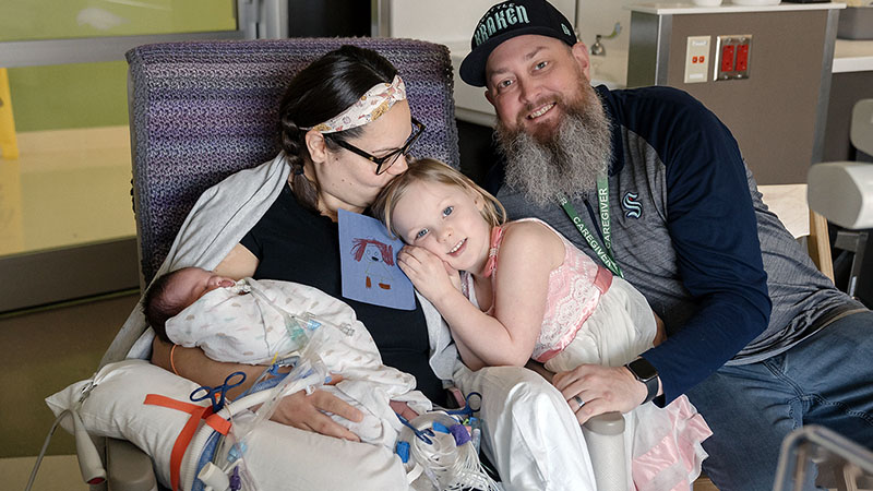 A mother, father, young daughter and baby daughter in a hospital
