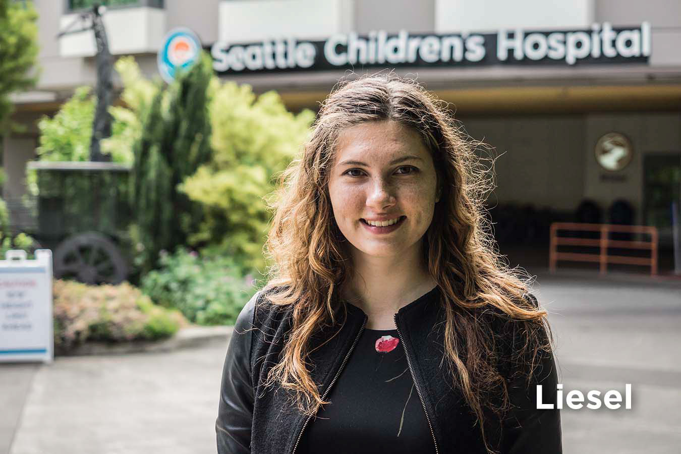 Seattle Children's Brain Tumor Program patient stands smiling in front of Seattle Children's Hospital building