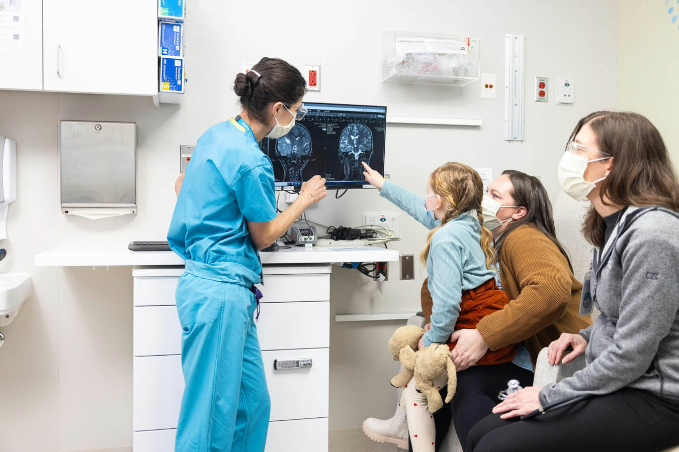 Seattle Children's Dr. Sarah Leary points to a scan of a patient's brain while the patient's family looks on