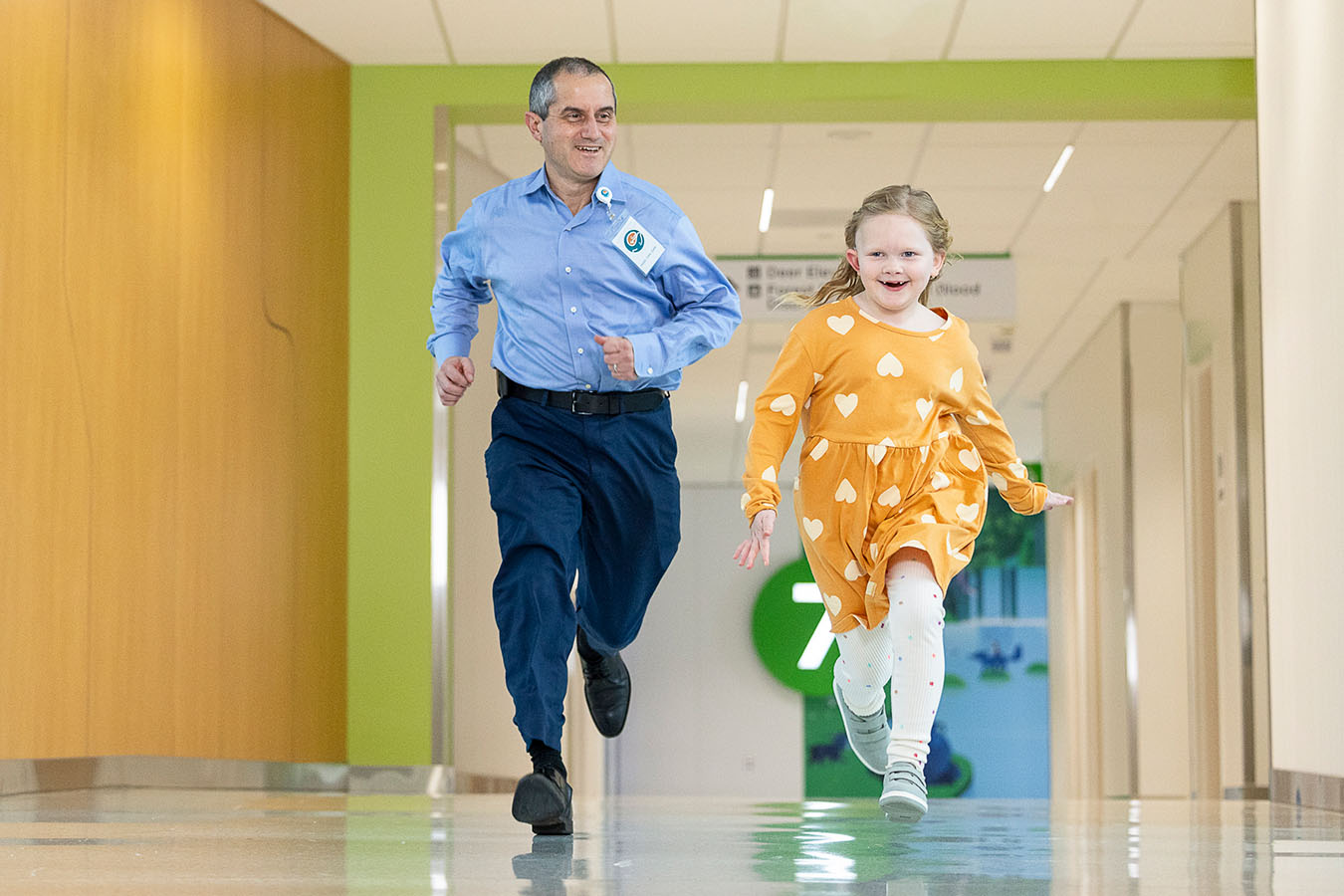 A Seattle Children's provider runs down a hosptial hallway with a brain tumor patient