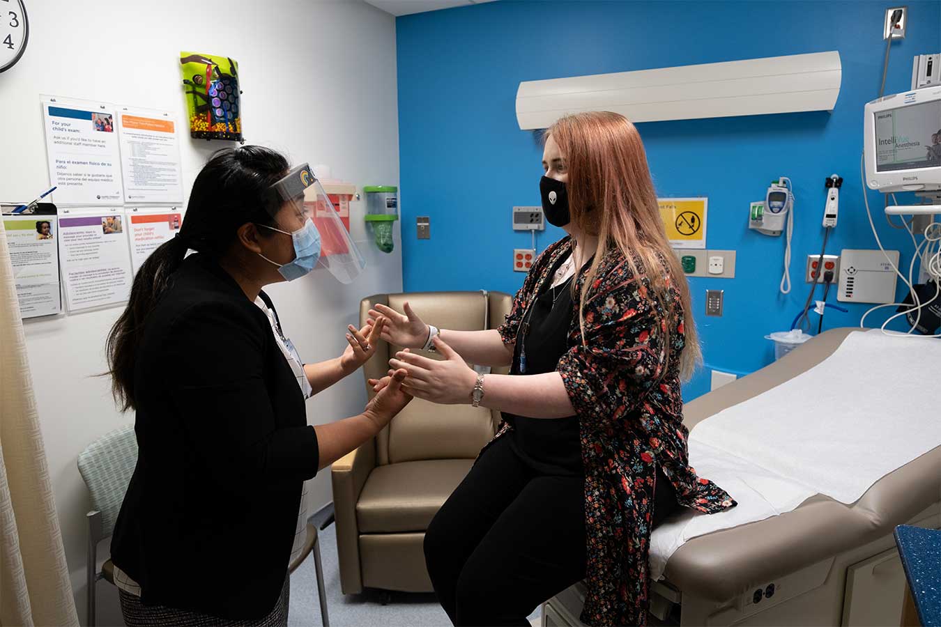 Dr Sato holds hands with a red haired patient at Seattle Children's Brain Tumor Program