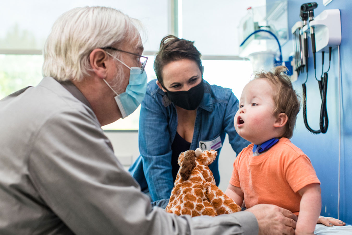 Seattle Children's Dr. Walker examining patient with stuffed giraffe toy