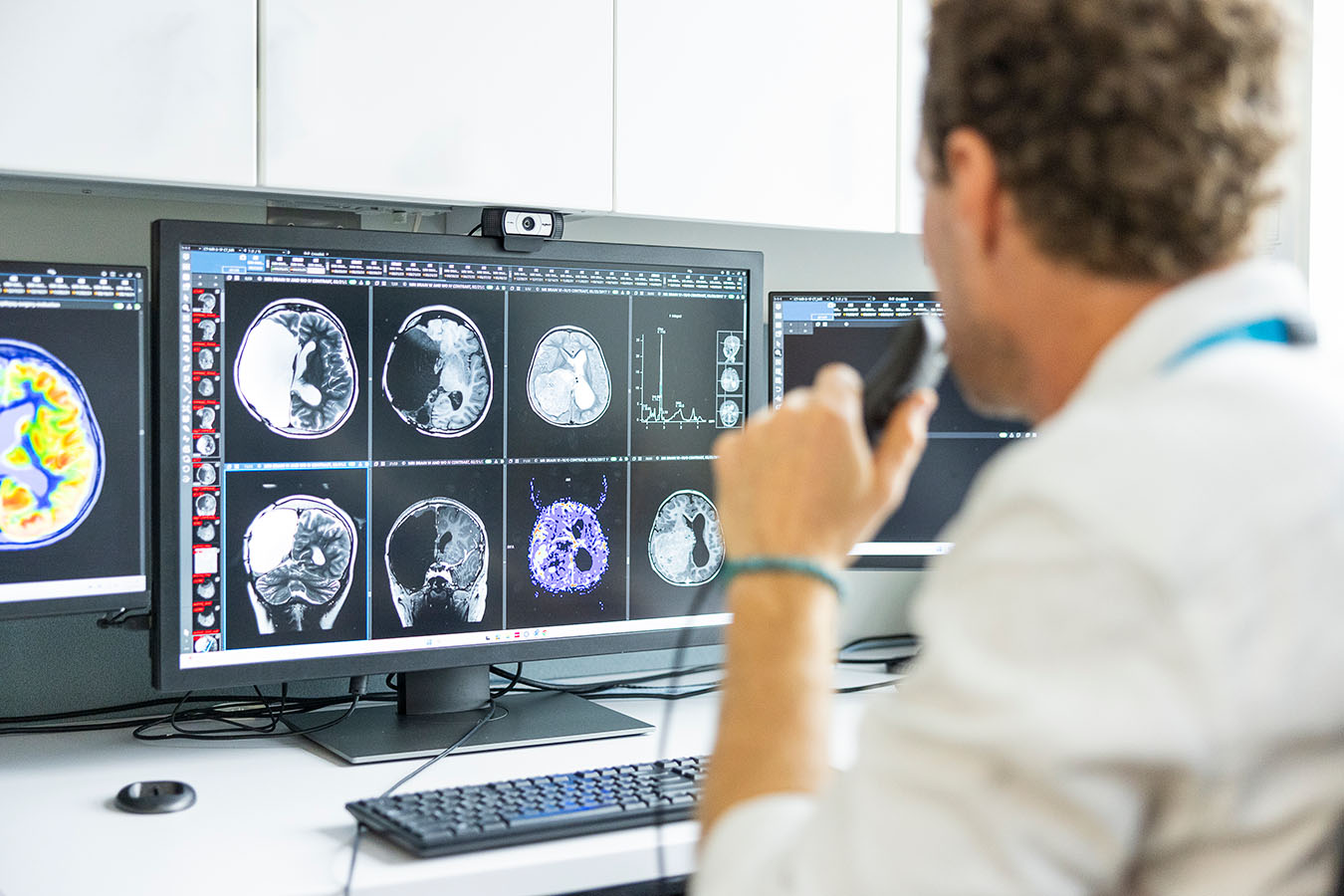 A clinician looks at a computer screen with brain scans