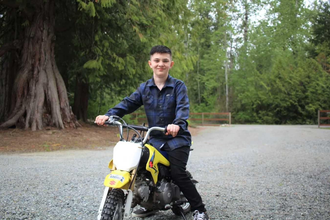 Teenager on yellow motorbike in woodland setting