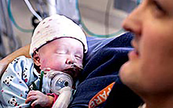 A baby in the NICU sleeping in an adult's arms