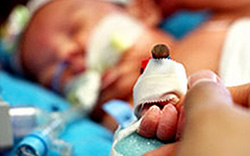 A baby in the NICU holding an adult's finger