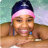 A girl smiles from the edge of a swimming pool