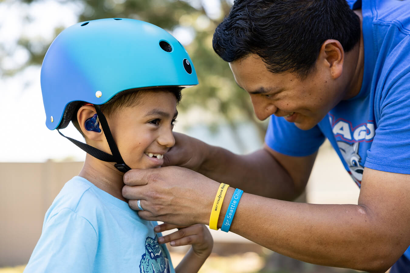 An adult buckles the bike helmet of a smiling child