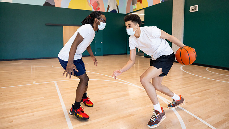 two teens playing indoor basketball