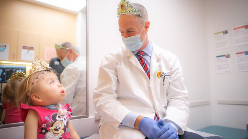 Patient Emma with Dr. Klane White both wear tiaras during a visit