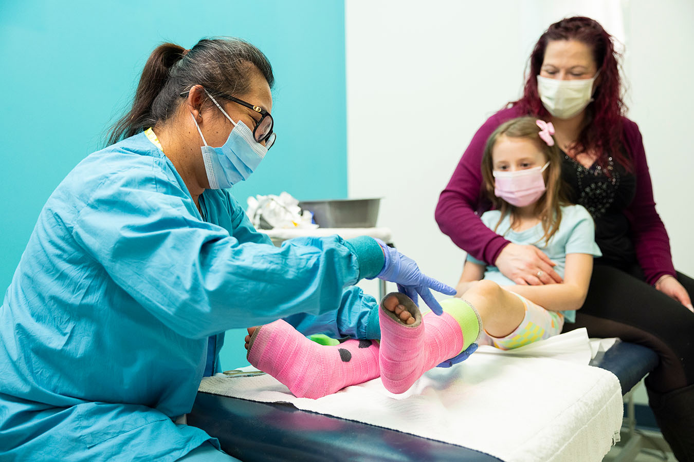 A Seattle Children's provider checks on a girl's legs, which are in casts