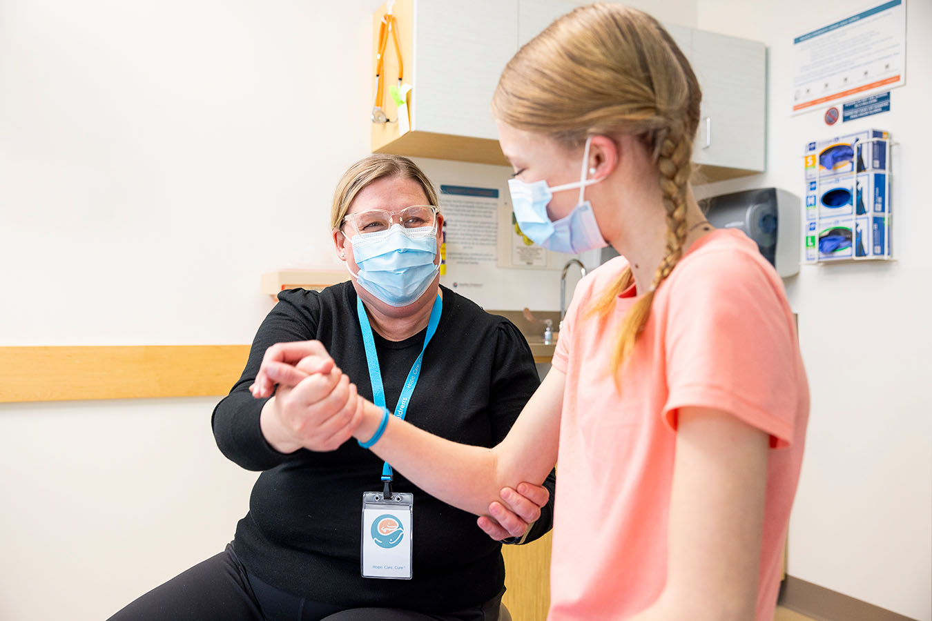 A Seattle Children's provider checks the arm strength of a teen girl