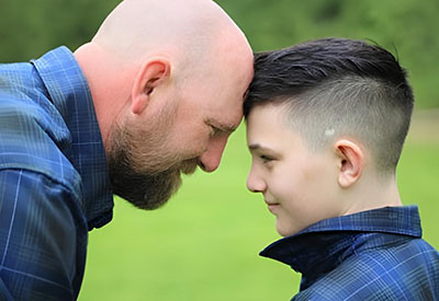 Thomas Gordon and his son facing each other and touching foreheads 