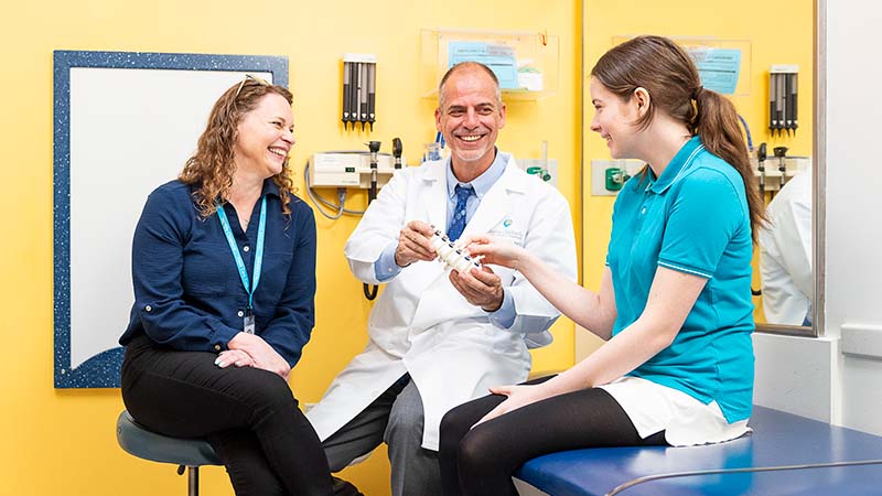 Two Seattle Children's providers show a model spine to a patient