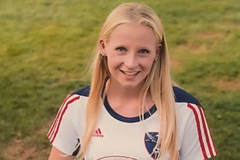 Female soccer player kneeling with ball