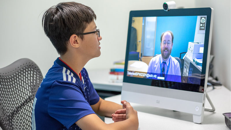 Teen looking at provider on computer screen during telehealth appointment