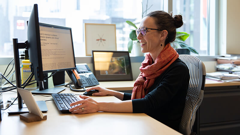 Woman wearing a headset, looking at dual computer monitors