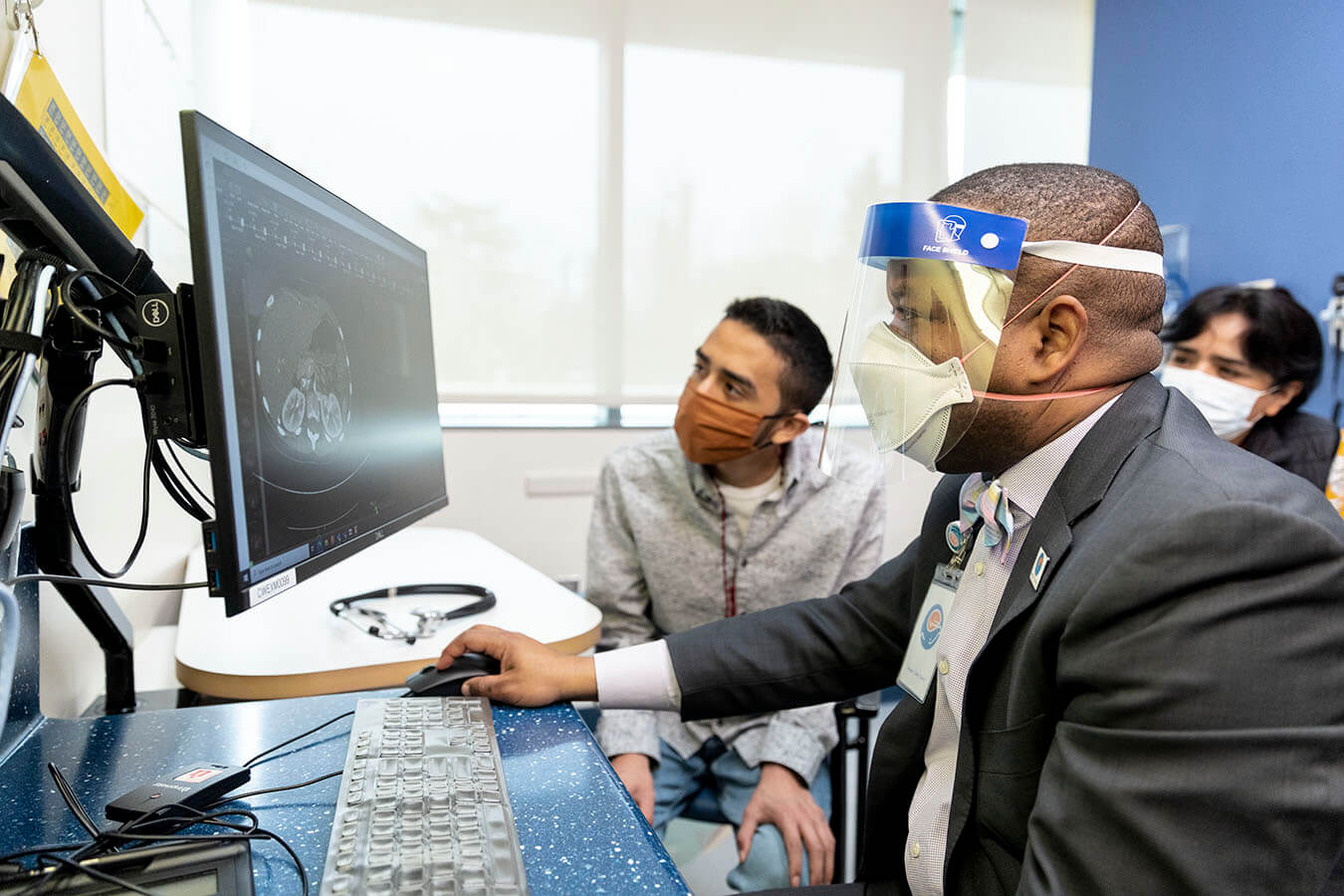 Dr. André Dick and patients examine a medical scan on a computer screen