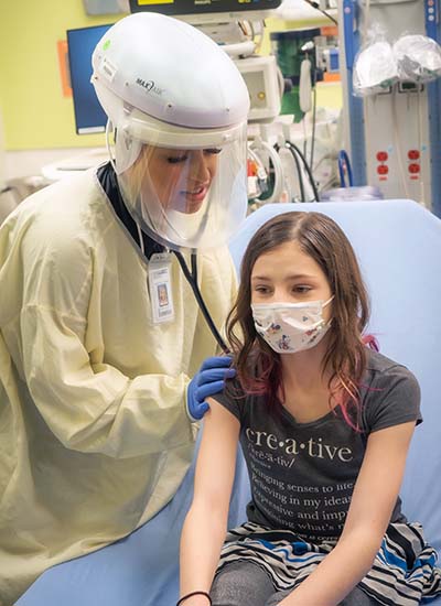 A girl in a mask is examined at one of Seattle Children's Urgent Care clinics.