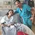 A patient and her doctor smiling for a photo together in her hospital room after her heart surgery. 