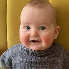 Baby in grey sweater smiles at the camera
