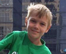 A boy in a green shirt smiling for the camera