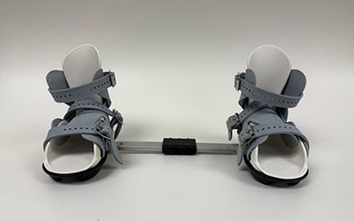 A pair of sandal-like boots attached a metal bar