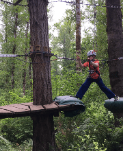 A boy on a zipline course in a forest