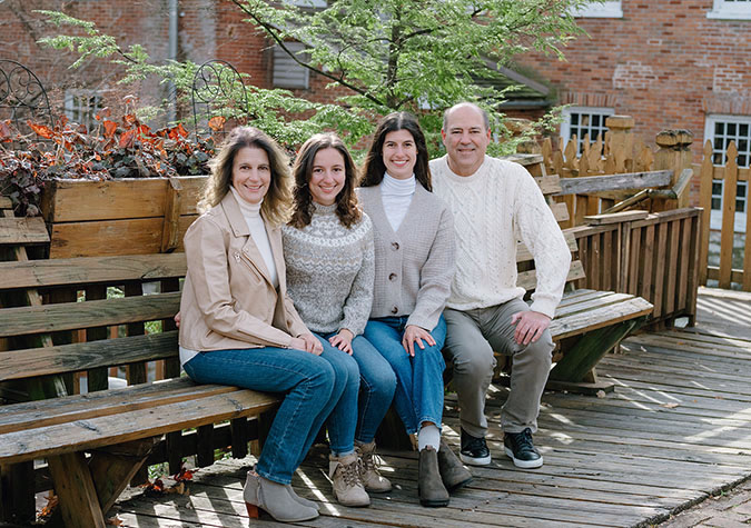 A family with two adult daughters sits on a bench