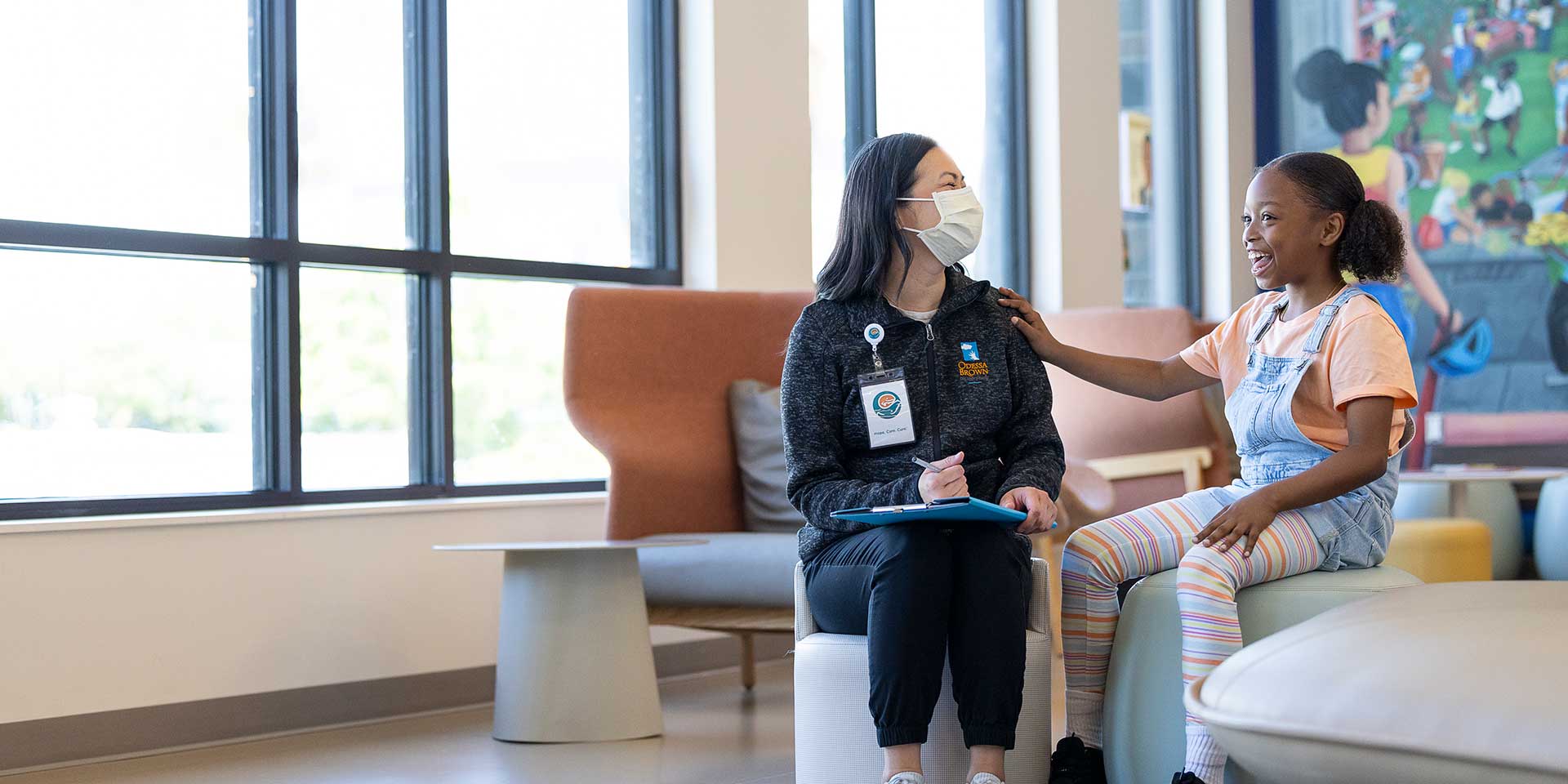 Girl with masked Seattle Children's nurse converse in sunny room