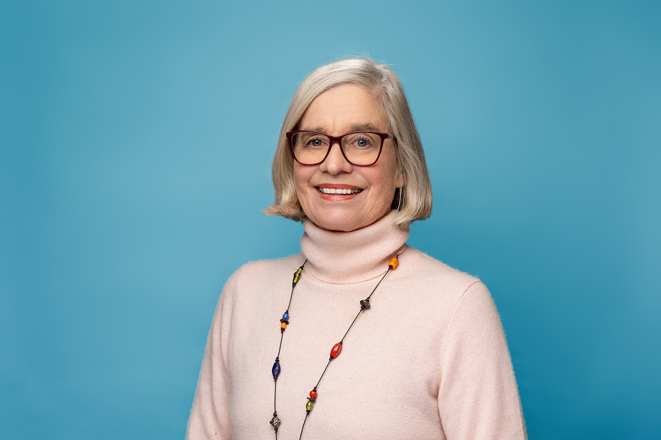 A woman stands against a blue background