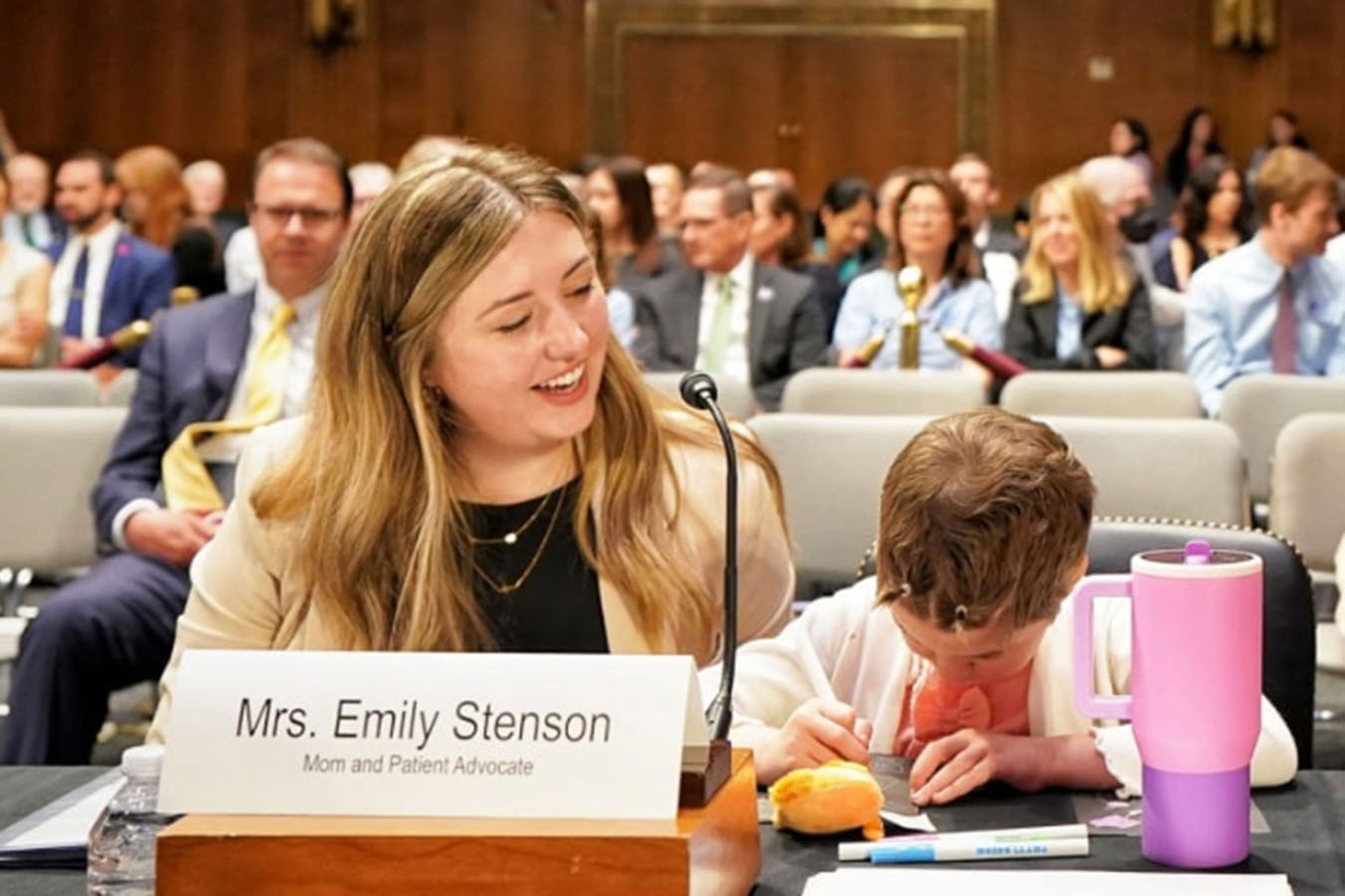 A woman at a congressional hearing sits next to a child