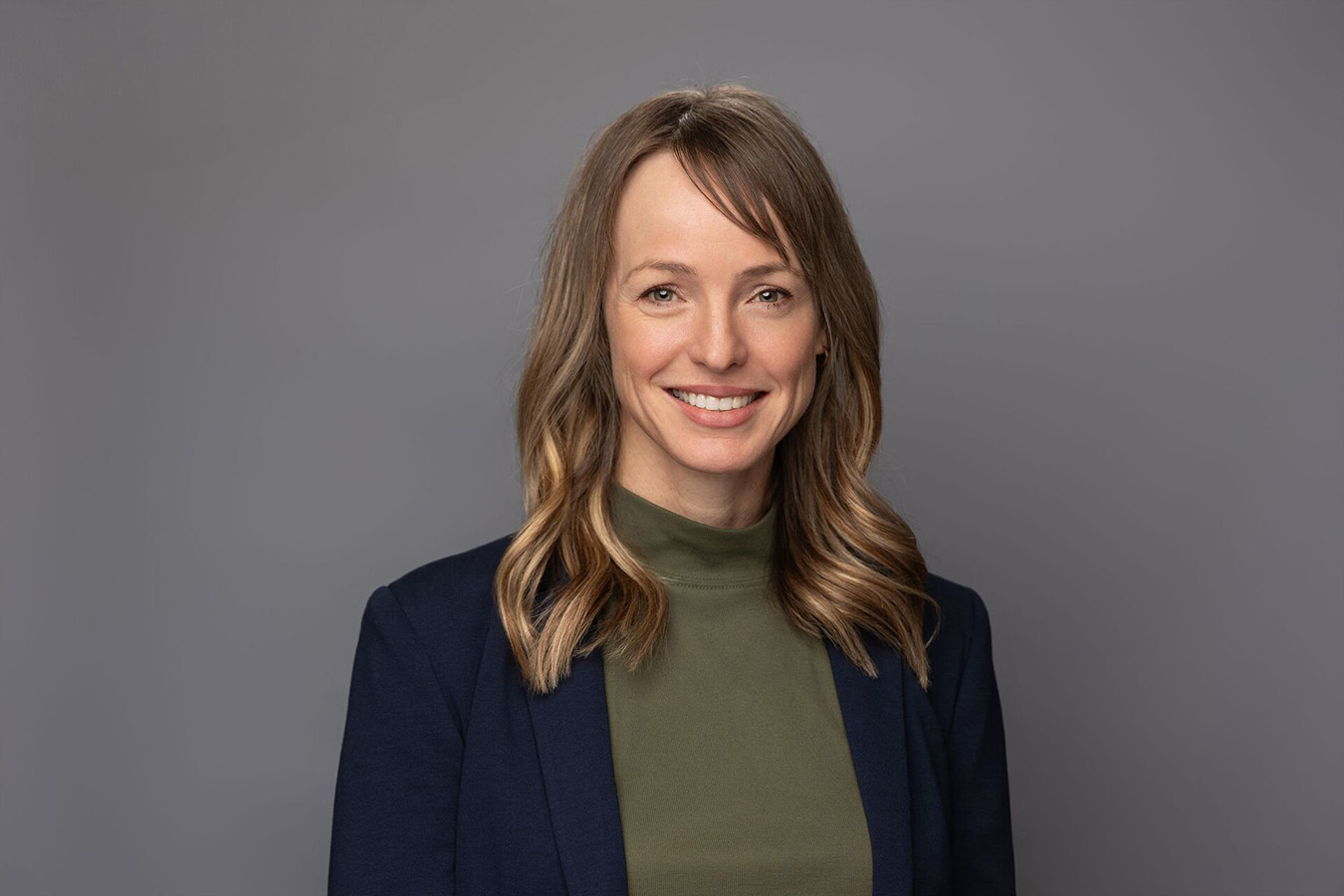 A woman stands against a grey background