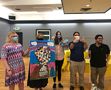 A group of students who attend classes at the center posing with a one-of-a-kind art piece they created that sold for $600.