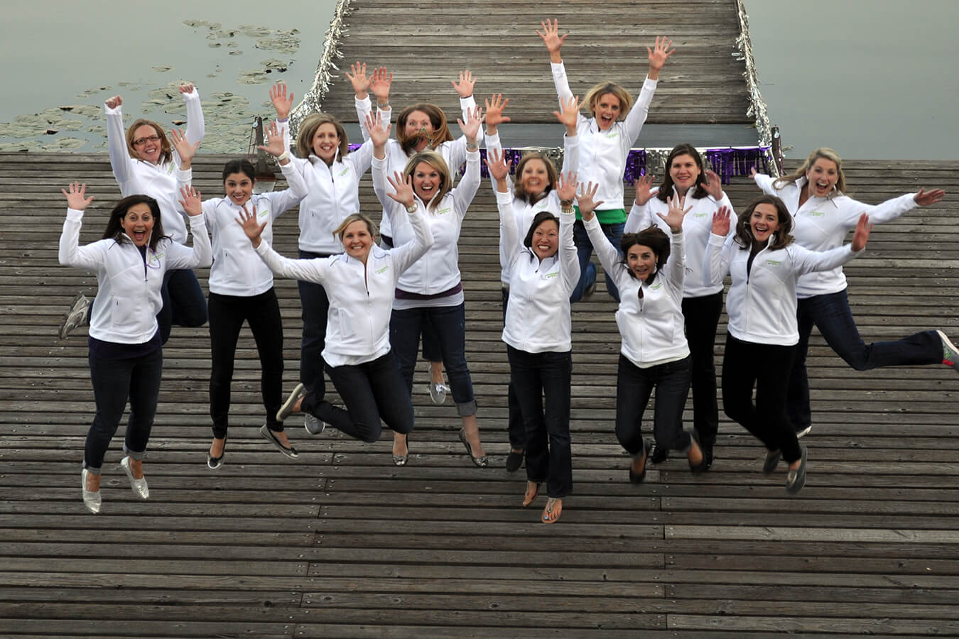 Women in white jackets jumping and smiling