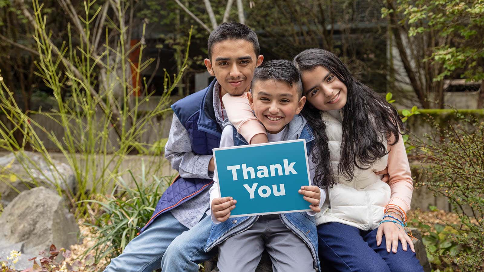 Three children holding a blue sign with the words thank you