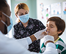 A doctor giving a nasal flu vaccine to a child